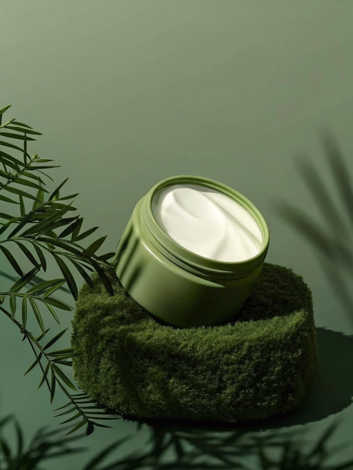 Open jar of green cream on a moss-covered stone among ferns